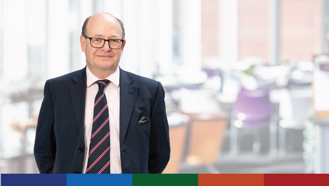 A photograph of a Scottish Government staff member dressed in a suit with an office background behind.